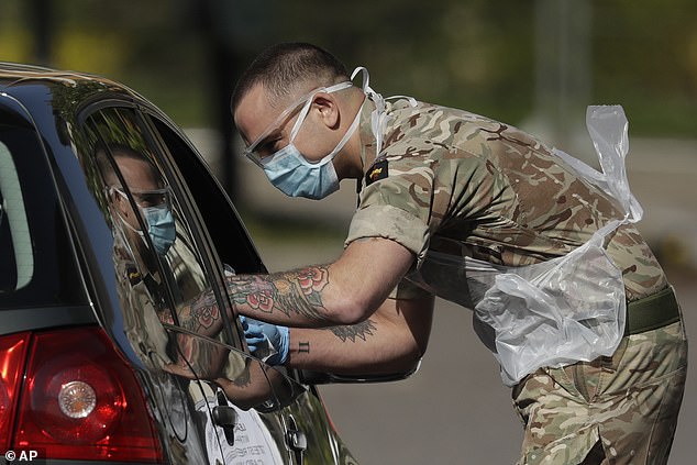 A NHS or care worker being tested by a soldier for COVID-19 at a drive-through testing centre in a car park at Chessington World of Adventures yesterday