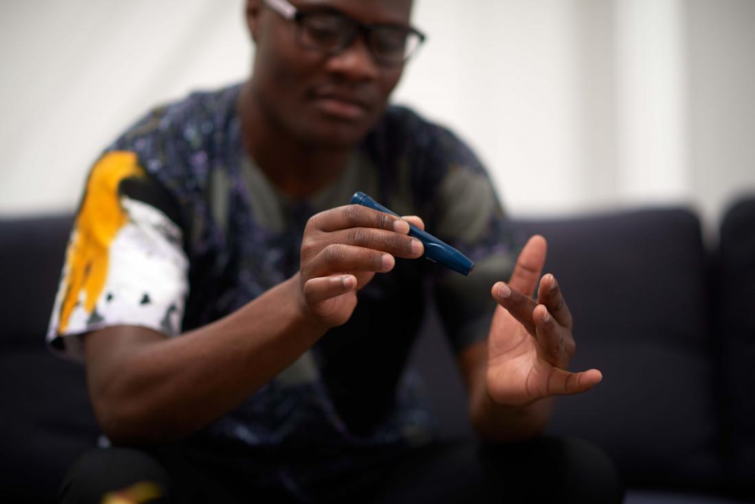 Black man taking blood sugar test using glucometer