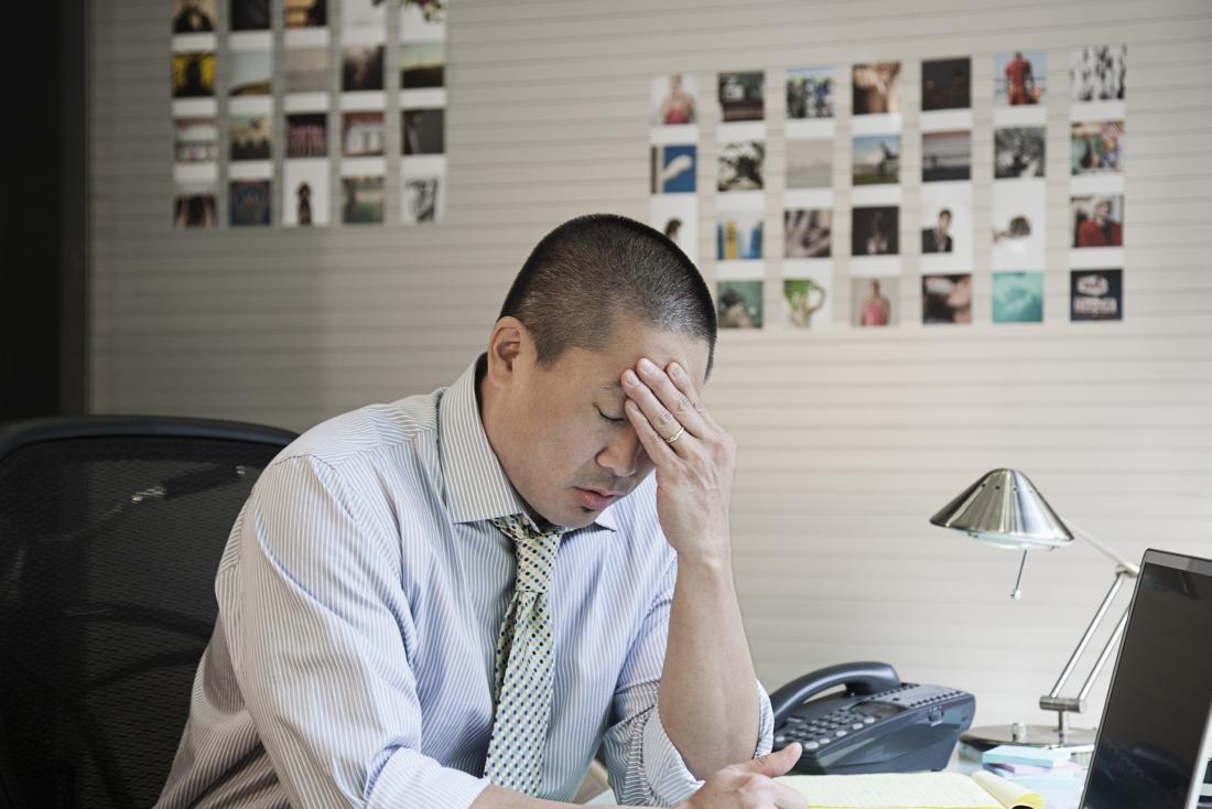 Stressed man at work holding head