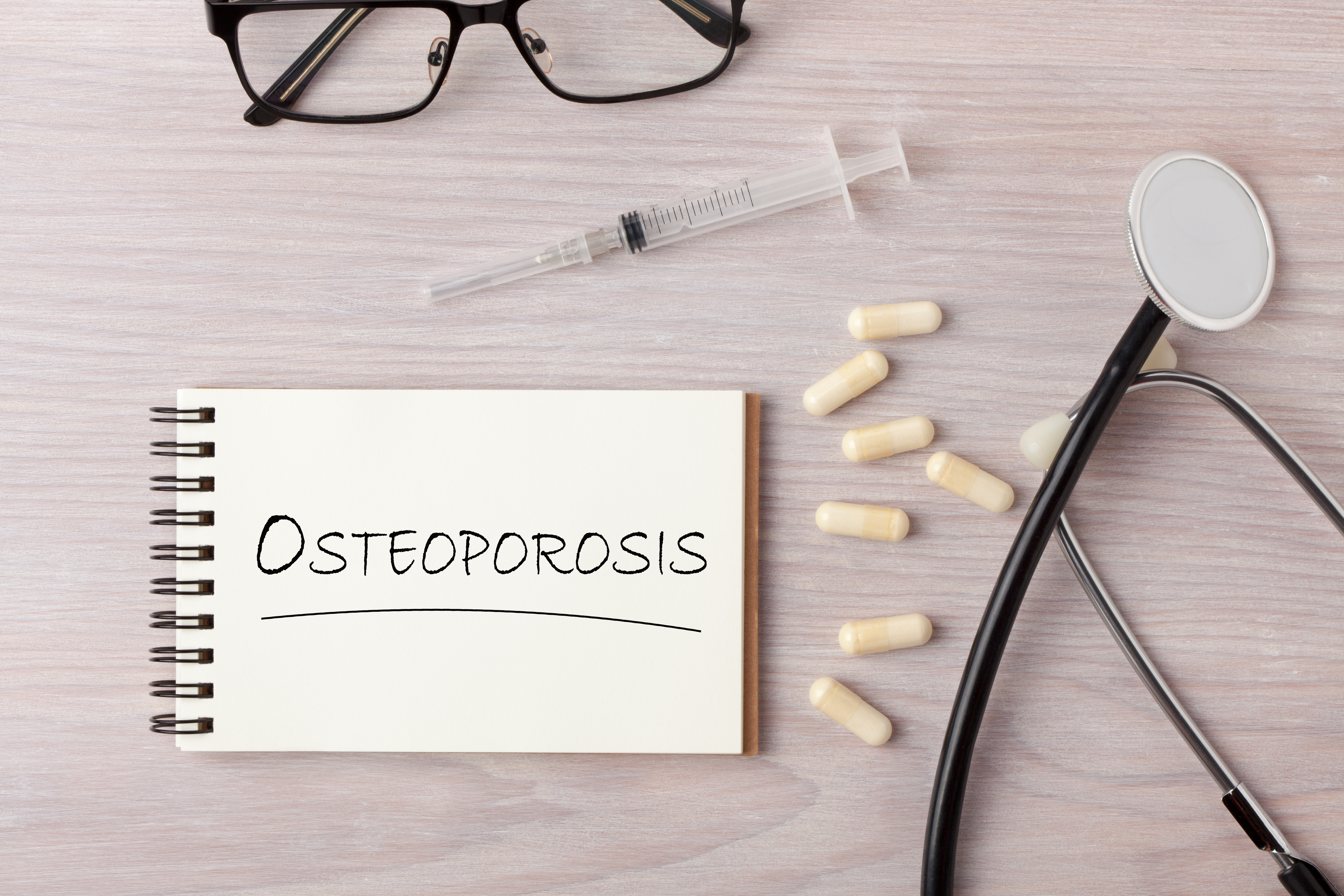 Osteoporosis written on a pad with medications and stethoscope nearby