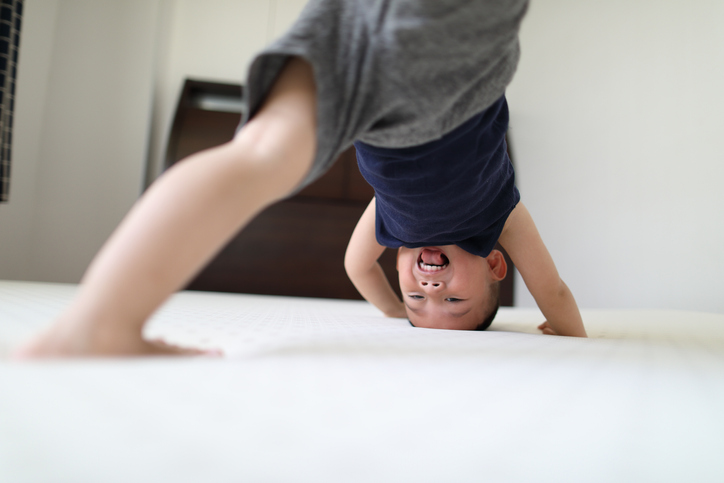Energetic young boy jumping on bed