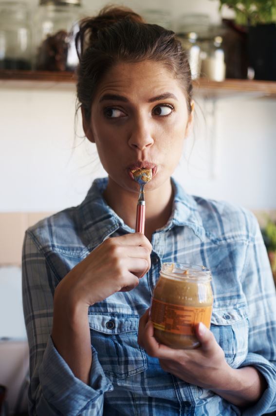Woman snacking on peanut butter bad habits